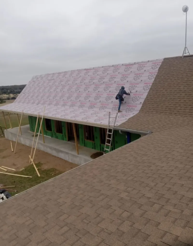 Worker preparing underlayment for a metal roof installation in Bridgewater Town